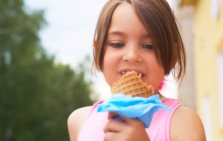 Closeup of ice cream held in hand by cute young girl. Little Caucasian girl eating ice cream in a waffle cone.の写真素材
