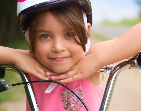 Close-up of a little girls face on bike looking at camera and smilingの写真素材