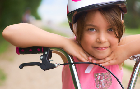 Close-up of a little girls face on bike looking at camera and smilingの写真素材