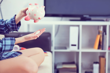 Girls hands holding a piggy Bank and pouring bitcoins out of it. Concept of the fall in the value of cryptocurrency.の写真素材