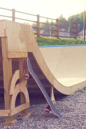 Skateboard standing on half pipe ramp at skatepark.の写真素材