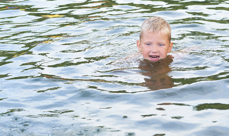 Portrait of happy fun little Caucasian boy swimming in the sea or lake.の写真素材