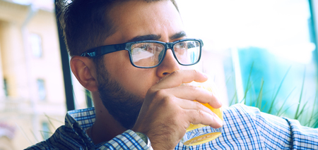 Arabic Egyptian young business attractive man having a coffee break and drinking orange juice in cafe.の写真素材