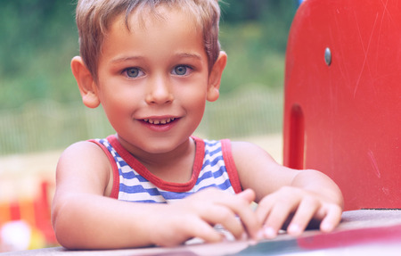 Little toddler boy in striped t-shirt having fun on playground on summer day.の写真素材