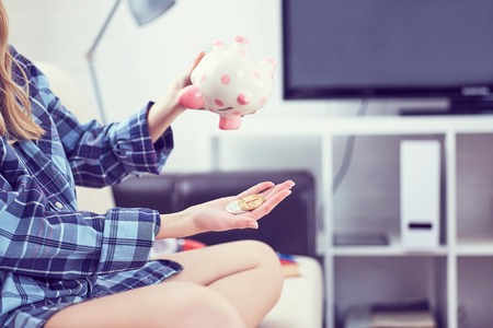 Girls hands holding a piggy Bank and pouring bitcoins out of it. Concept of the fall in the value of cryptocurrency.の写真素材