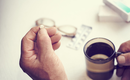 Little white pill in a Seniors hands. Painful old age. Caring for the health of the elderlyの写真素材