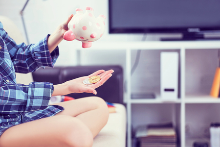 Girls hands holding a piggy Bank and pouring bitcoins out of it. Concept of the fall in the value of cryptocurrency.の写真素材