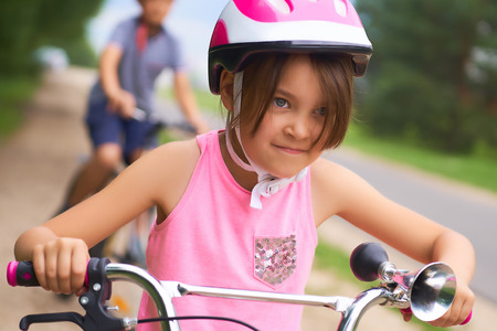 Portrait of a litte girl in a pink safety helmet driving her bike.の写真素材