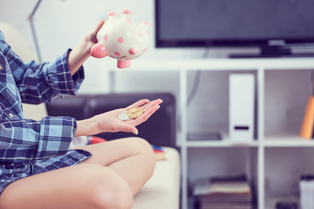 Girl's hands holding a piggy Bank and pouring bitcoins out of it. Money debt, bankruptcy and lost savings concept. Concept of the fall in the value of cryptocurrency.の写真素材