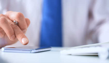 Businessman using smart phone in office close up.の写真素材