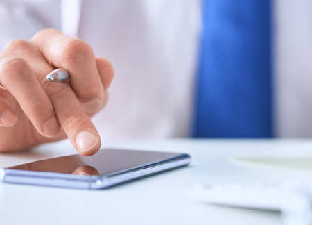 Businessman using smart phone in office close up.の写真素材