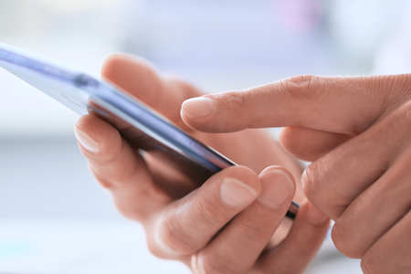 Businessman using smart phone in office close up.の写真素材