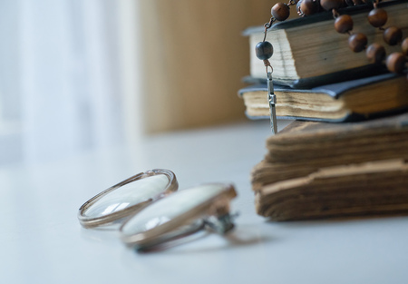 The rosary beads on Catholic Church liturgy books and old glasses on the side of them.の写真素材