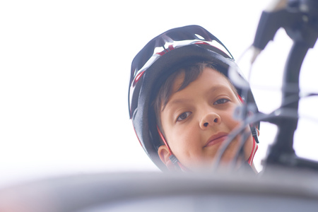 Teenager boy in protective helmet sitting on his bicycle in park on summer day and looking into the camera looking down.の写真素材