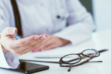 Female doctor explaining patient symptoms or asking a question as they discuss together in a consultation. Just hands over the table.の写真素材