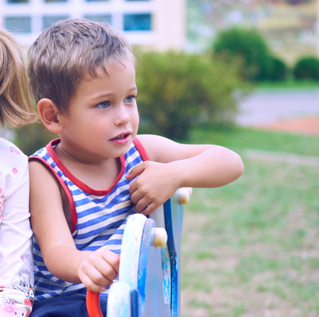Two little children playing at the playground. Image of emotional cheerful adorable Caucasian kids...