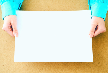 Blank paper in womans hands waiting for idea or advertising lettering.の写真素材