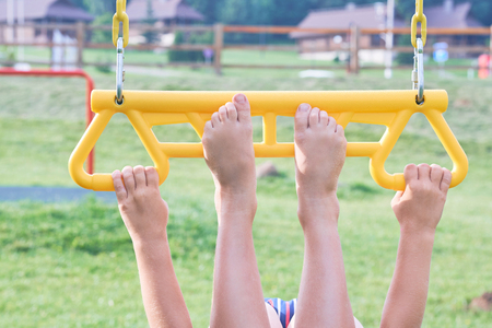 Child on monkey bars. Kid at beach playground. Little boy hanging on gym activity center of preschool play ground. Healthy outdoor activity for kids. Sport for young children.の写真素材