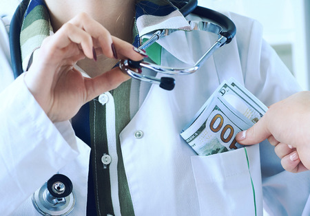 Medicine doctor receiving large amount of dollar banknotes as a bribe. Corruption in Health Care...