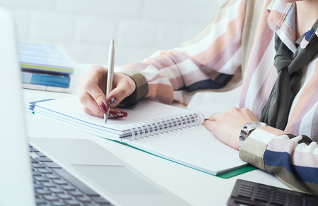 Side view of business woman making notes with silver pen in office background. Business finance savings loan and credit concept.の写真素材