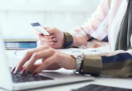 Female office worker hands holding credit card, typing on the keyboard of laptop, online ine shopping detail close up.の写真素材