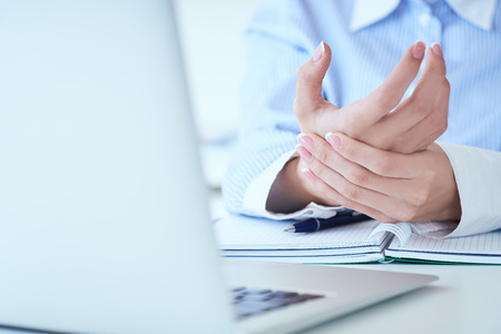Young woman holding her wrist close-up . Pain from using computer. Office syndrome hand pain by occupational disease.の写真素材