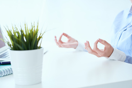 Calm businesswoman meditating at work, focus on female hands in mudra, close up view. Peaceful mindful employee practicing exercises at workplace.の写真素材
