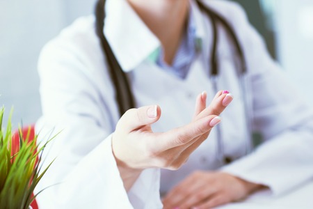 Female doctor explaining patient symptoms or asking a question as they discuss together in a consultation. Just hands over the table.の写真素材