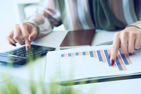 A womans hand pointing on summary report chart and calculate finance in office close-up.の写真素材