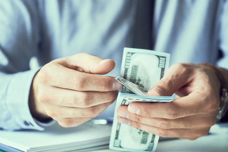 Businessman count the new us dollars paper money. Form of a bribe or salary.の写真素材