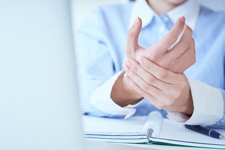 Young woman holding her wrist close-up . Pain from using computer. Office syndrome hand pain by occupational disease.の写真素材