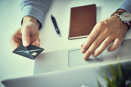 Businessman holding credit card and typing on laptop for online shopping and payment makes a...