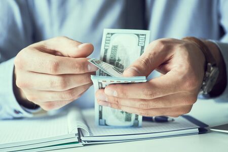 Businessman count the new us dollars paper money. Form of a bribe or salary.の写真素材