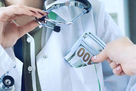 Medicine doctor receiving large amount of dollar banknotes as a bribe. Corruption in Health Care...