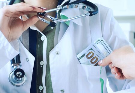 Medicine doctor receiving large amount of dollar banknotes as a bribe. Corruption in Health Care...