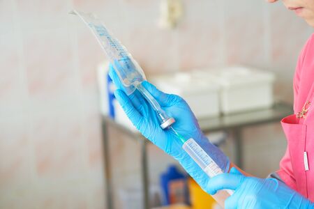 Nurse holding a medical syringe and solution for dropper in hands and putting medicine inside it. Injection preparation in hospital.の写真素材