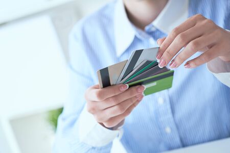 Woman hand holding various credit cards and making choice with another hand close-up.の写真素材