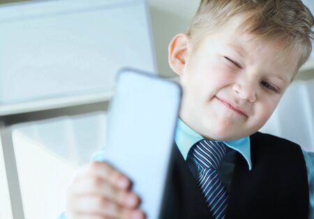 Stylish fashion business boy making selfie on mobile phone in office background.の写真素材