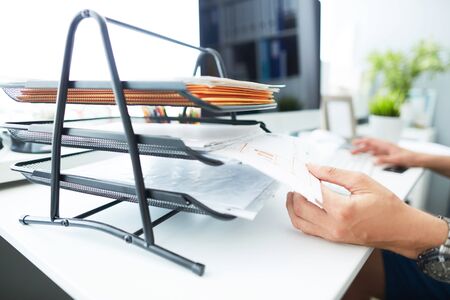 Close-up of a mans hand pulling files from office shelves. White collar job, digital shopping,...