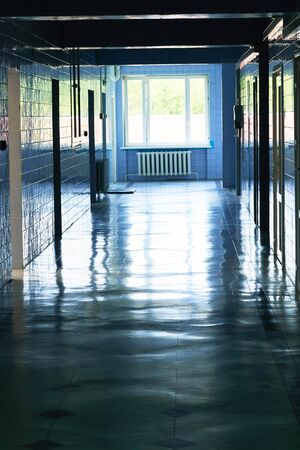 Blurry photo of hospital walk way with bright blue lighting. White floor with cool tone color with light tunnel in the middle of picture. Toned photo.の写真素材