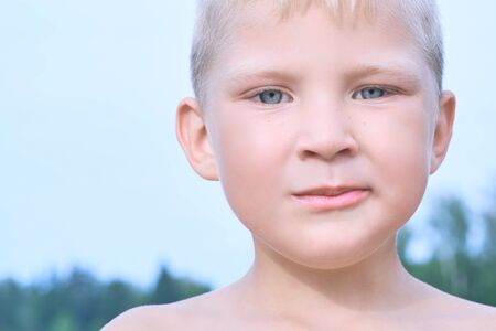 Little Caucasian blonde boy eating an pear on a hot summer day at the beach.