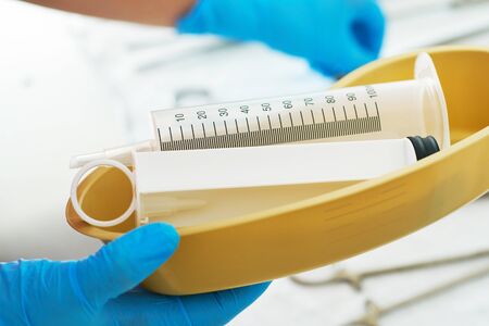 Syringe for gastric lavage in the hands of a nurse in the operating room. Nurse preparing medical instruments for operation.の写真素材