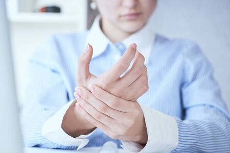 Young woman holding her wrist close-up . Pain from using computer. Office syndrome hand pain by occupational disease.の写真素材