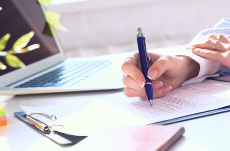 Businesswoman sitting at office desk signing a contract or making notes.