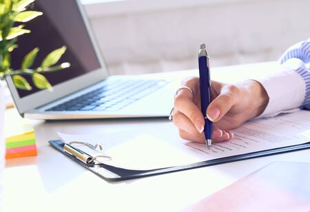 Businesswoman sitting at office desk signing a contract or making notes.