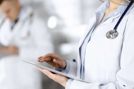 Unknown woman doctor is checking some data at computer tablet, close up. Young doctors at work in a hospital. Medicine and healthcare conceptの写真素材