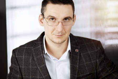 Friendly adult businessman in grey jacket. Business headshot or portrait in sunny office