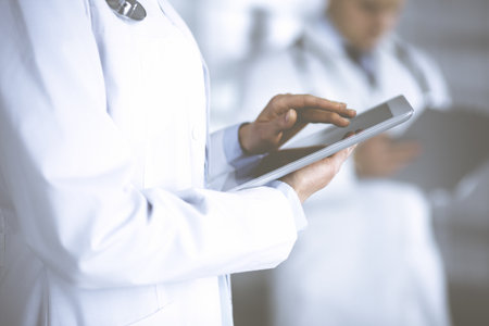 Unknown woman doctor is checking some data at computer tablet, close up. Young doctors at work in a hospital. Medicine and healthcare conceptの写真素材