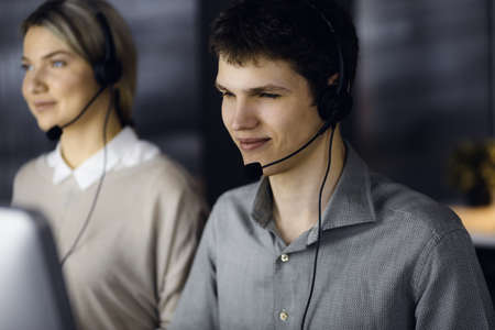Diverse people group in call center. Businessman talking by headset while sitting in modern officeの写真素材