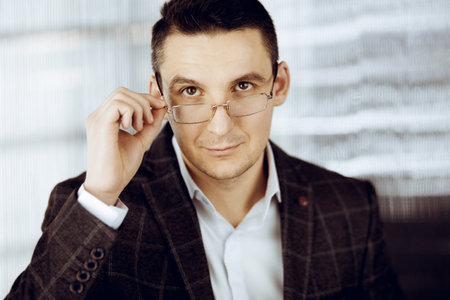 Friendly adult businessman in grey jacket. Business headshot or portrait in sunny officeの写真素材